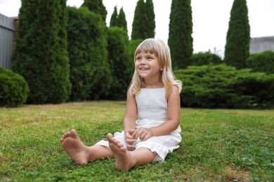 Barefoot little girl on green grass outdoors. Child enjoying beautiful nature