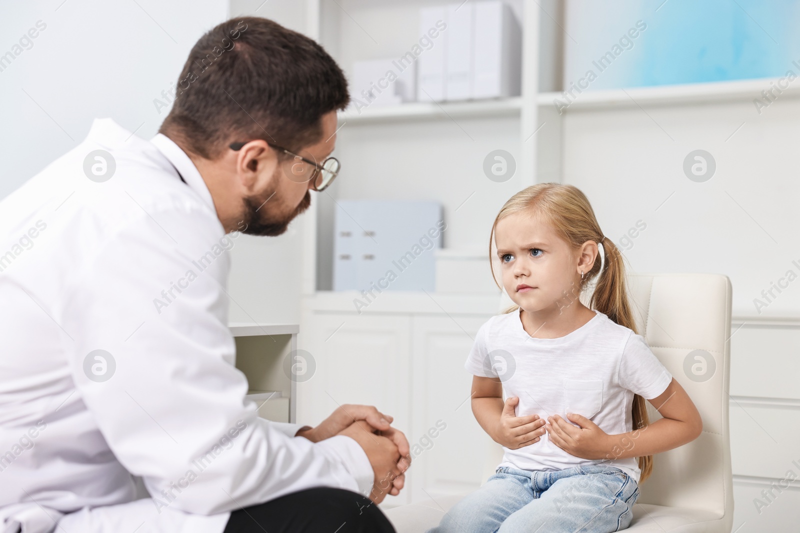 Photo of Doctor consulting little girl with stomach pain in hospital