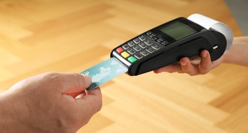 Customer making payment by putting credit card into POS machine indoors, closeup