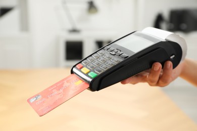 Photo of Cashier taking credit card payment with POS machine indoors, closeup