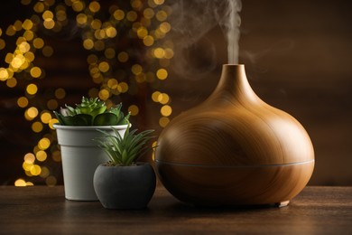 Aroma oil diffuser and houseplants on wooden table