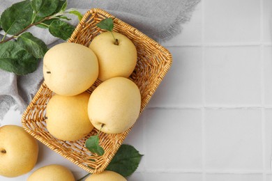 Photo of Delicious fresh apple pears and green leaves on white tiled table, top view. Space for text