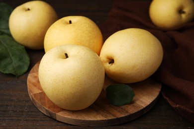 Photo of Delicious fresh apple pears and green leaves on wooden table, closeup