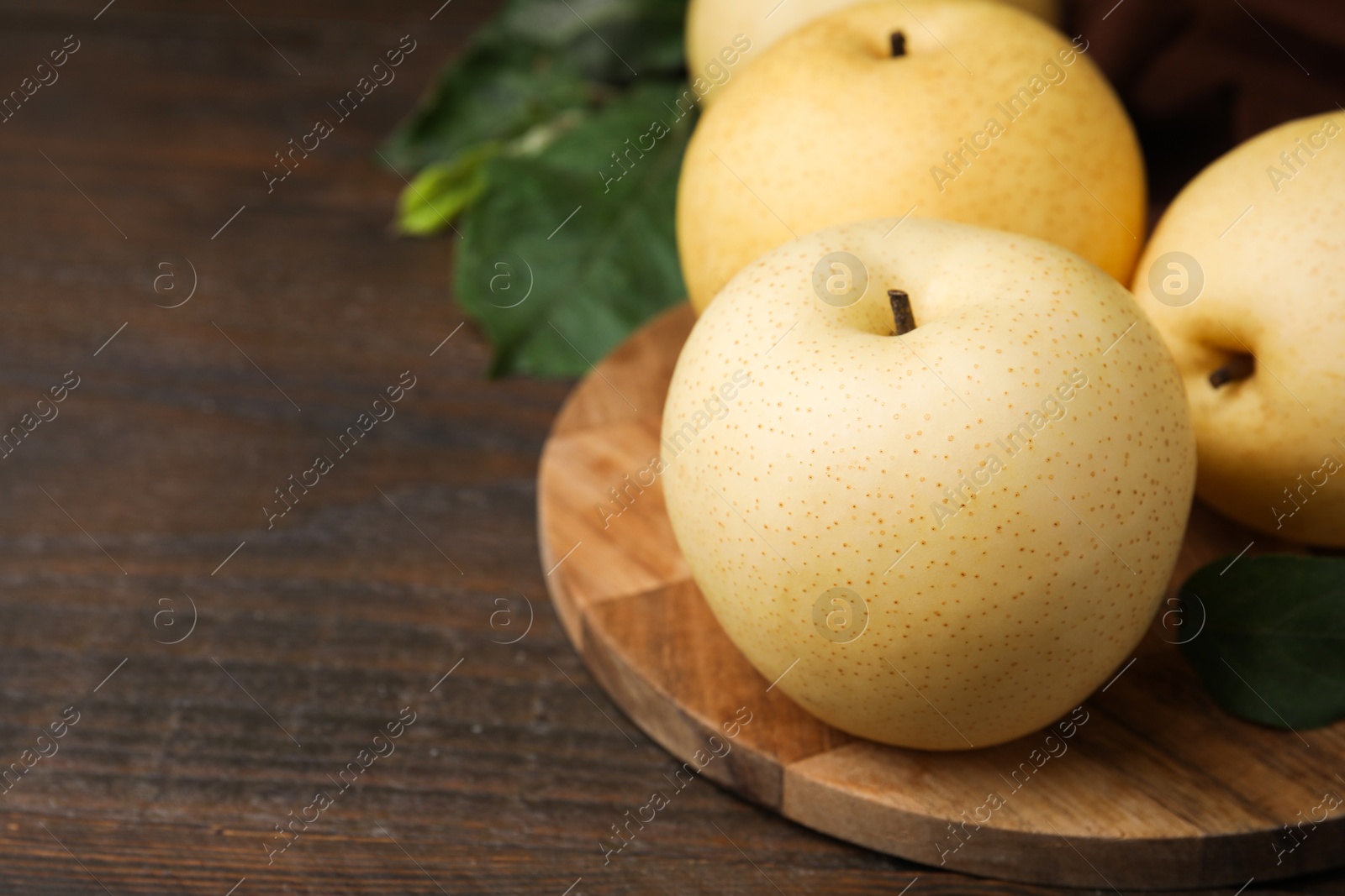 Photo of Delicious fresh apple pears and green leaves on wooden table, closeup. Space for text