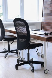 Photo of Black chairs, laptop and desk in office