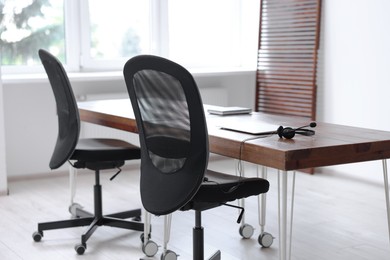 Photo of Black chairs, laptop and desk in office