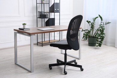 Black chair, laptop and desk in office