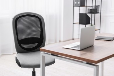 Photo of Black chair, laptop and desk in office