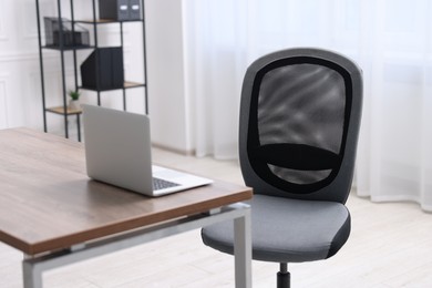 Black chair, laptop and desk in office