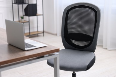 Photo of Black chair, laptop and desk in office