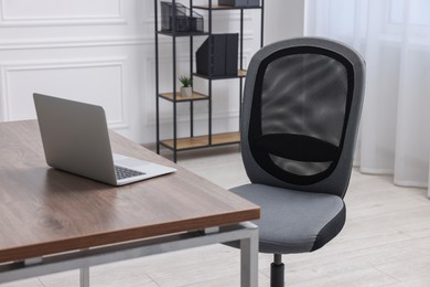 Black chair, laptop and desk in office