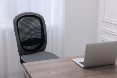 Black chair, laptop and desk in office