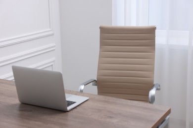 Photo of Beige leather chair, laptop and desk in office