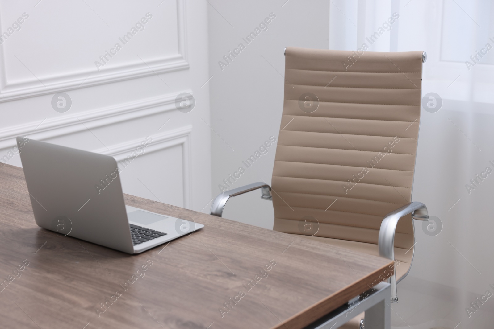 Photo of Beige leather chair, laptop and desk in office