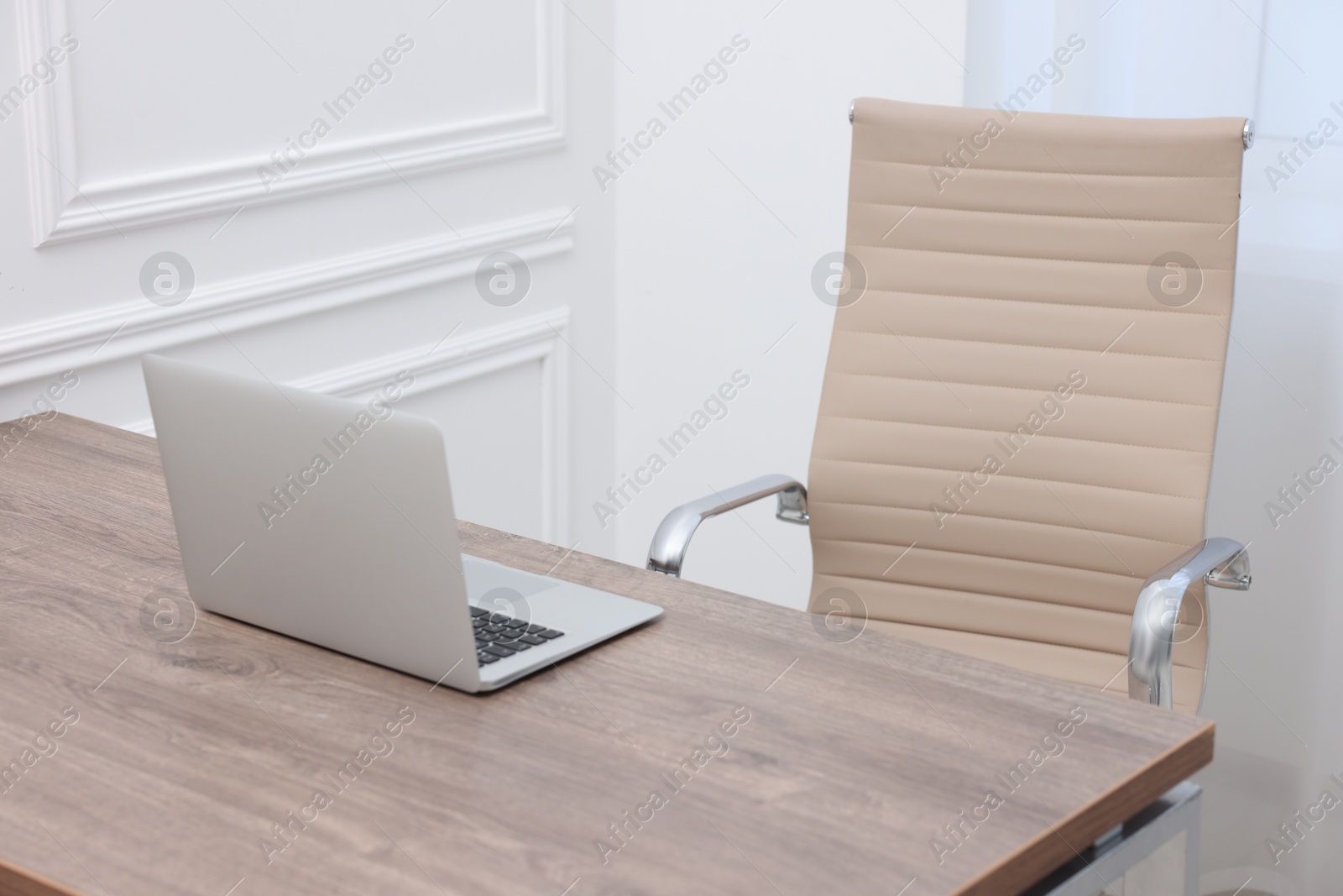 Photo of Beige leather chair, laptop and desk in office