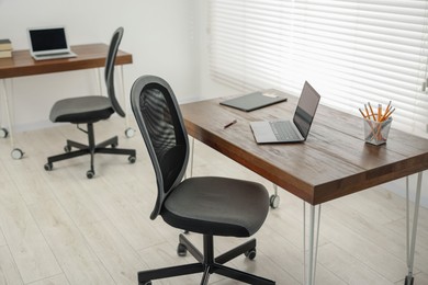 Black chair, laptop and desk in office