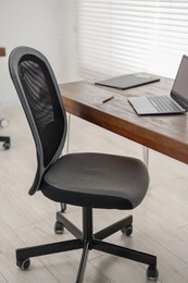 Black chair, laptop and desk in office