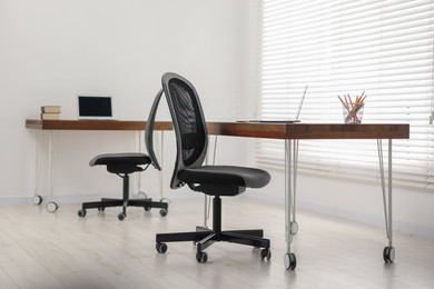 Photo of Black chair, laptop and desk in office