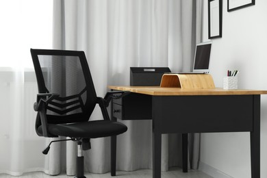 Black chair, laptop and desk in office