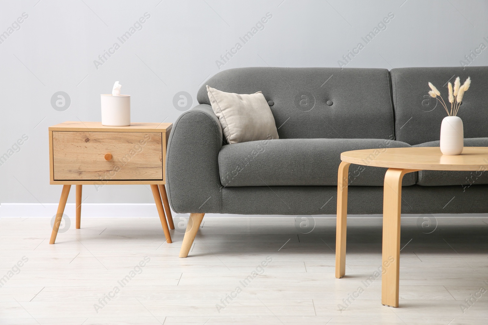 Photo of Comfortable sofa and tables near grey wall in room