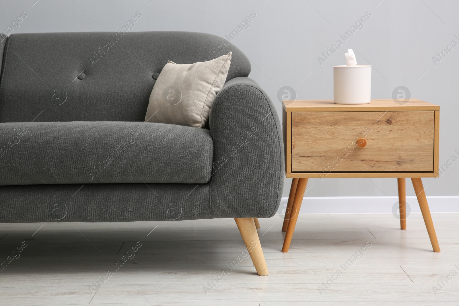 Photo of Comfortable sofa and table near grey wall in room