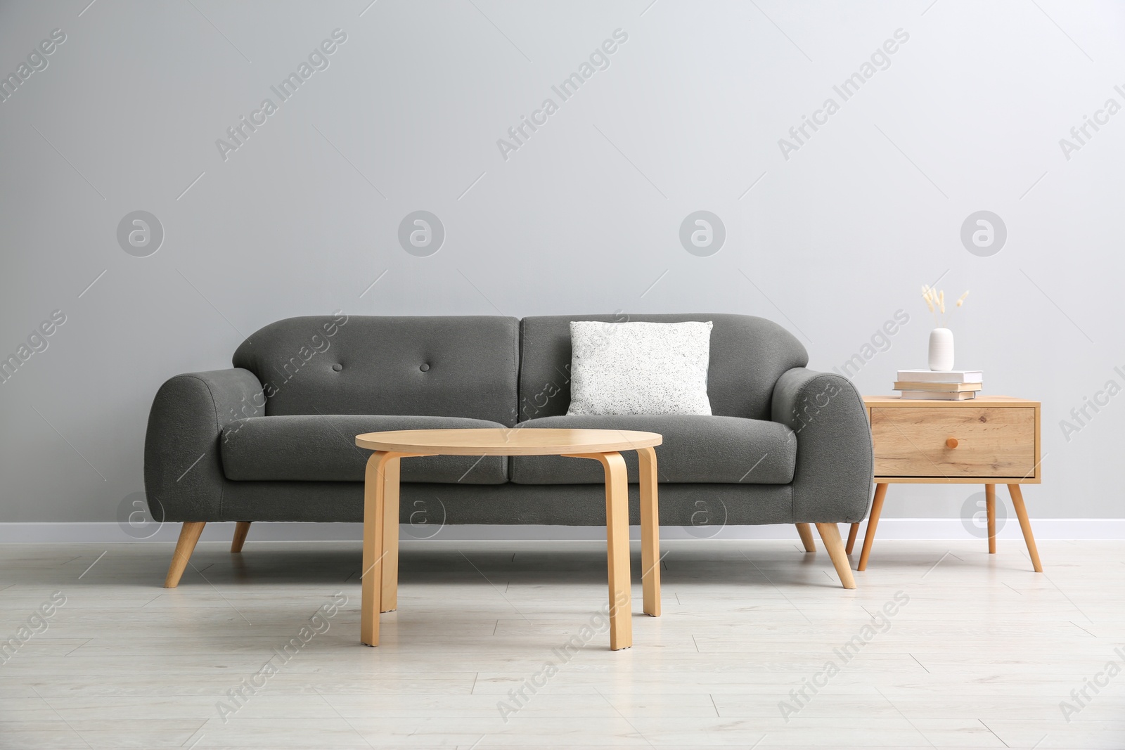 Photo of Comfortable sofa and tables near grey wall in room