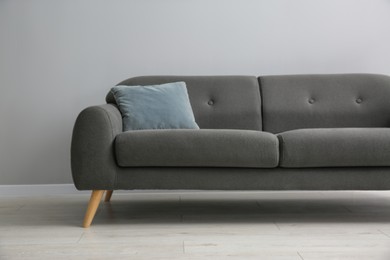 Photo of Comfortable sofa with cushion near grey wall in room