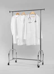 Doctor's coats with stethoscope on clothing rack against white background