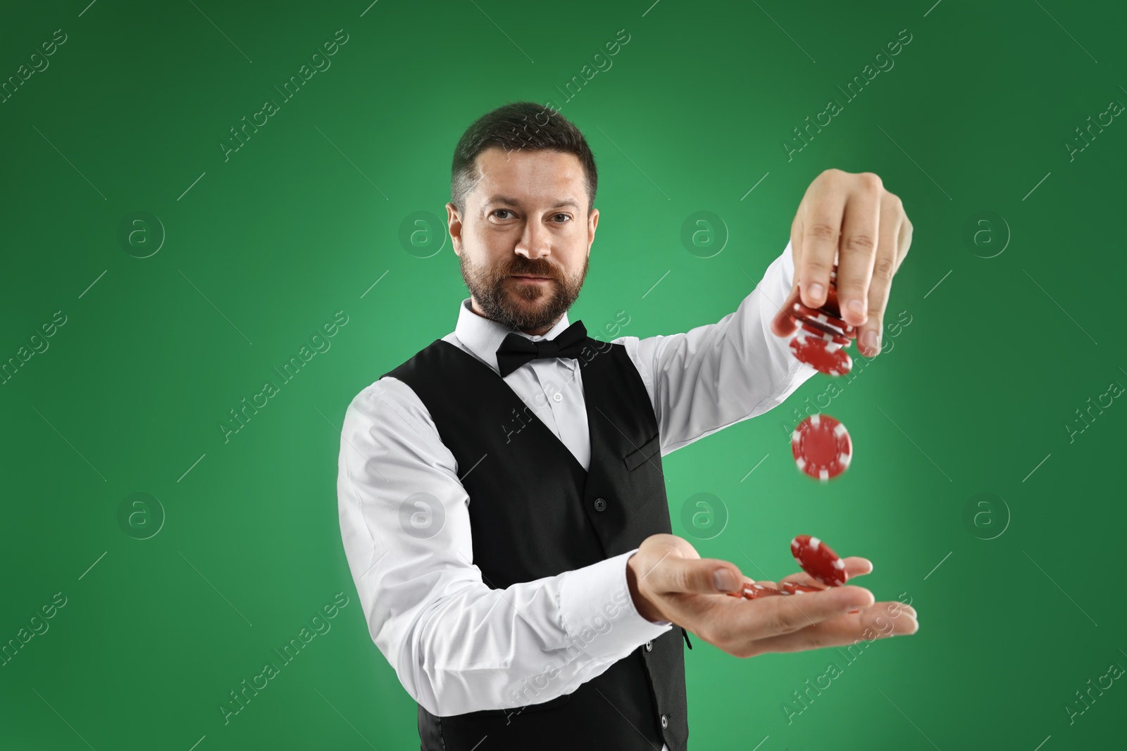 Photo of Professional croupier with casino chips on green background