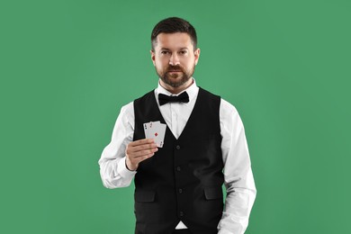 Photo of Professional croupier with playing cards on green background