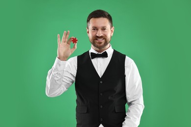 Photo of Croupier with casino chip on green background