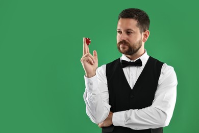 Croupier with casino chip on green background, space for text