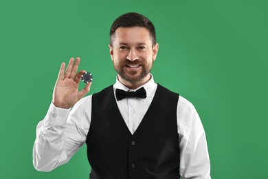 Croupier with casino chip on green background