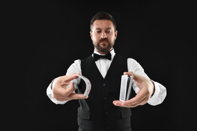 Photo of Professional croupier shuffling cards on black background