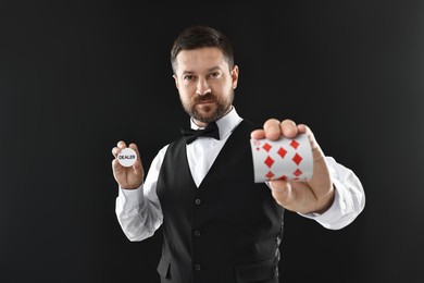 Photo of Croupier holding card and dealer button on black background