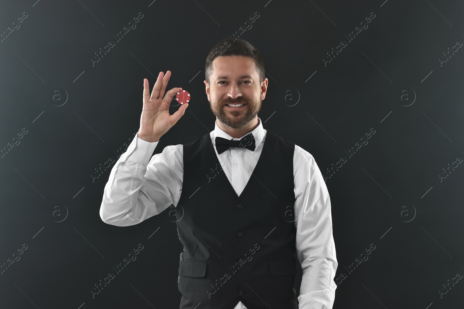 Photo of Croupier with casino chip on black background