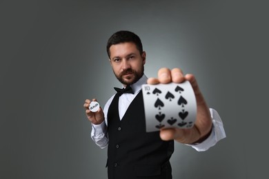 Photo of Croupier holding card and dealer button on grey background