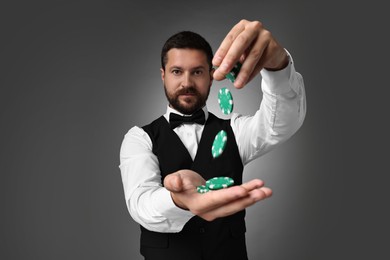 Croupier with casino chips on grey background