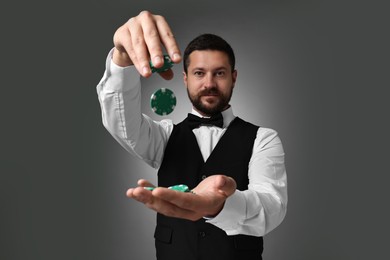 Photo of Croupier with casino chips on grey background