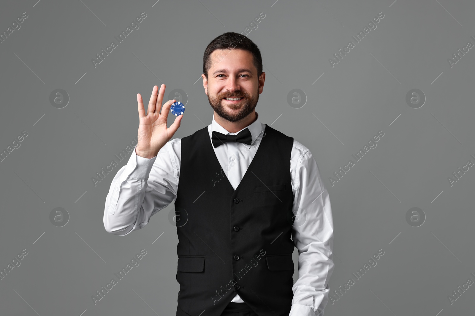 Photo of Croupier with casino chip on grey background