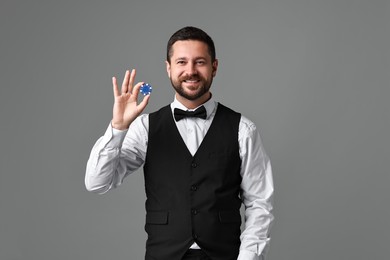 Photo of Croupier with casino chip on grey background