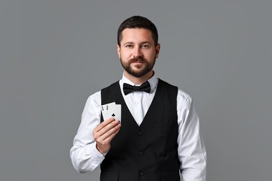 Photo of Professional croupier with playing cards on grey background