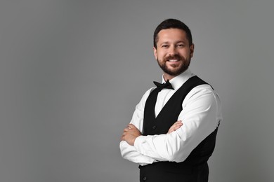 Portrait of professional croupier on grey background, space for text