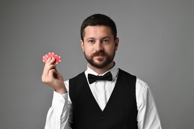 Photo of Croupier with casino chips on grey background