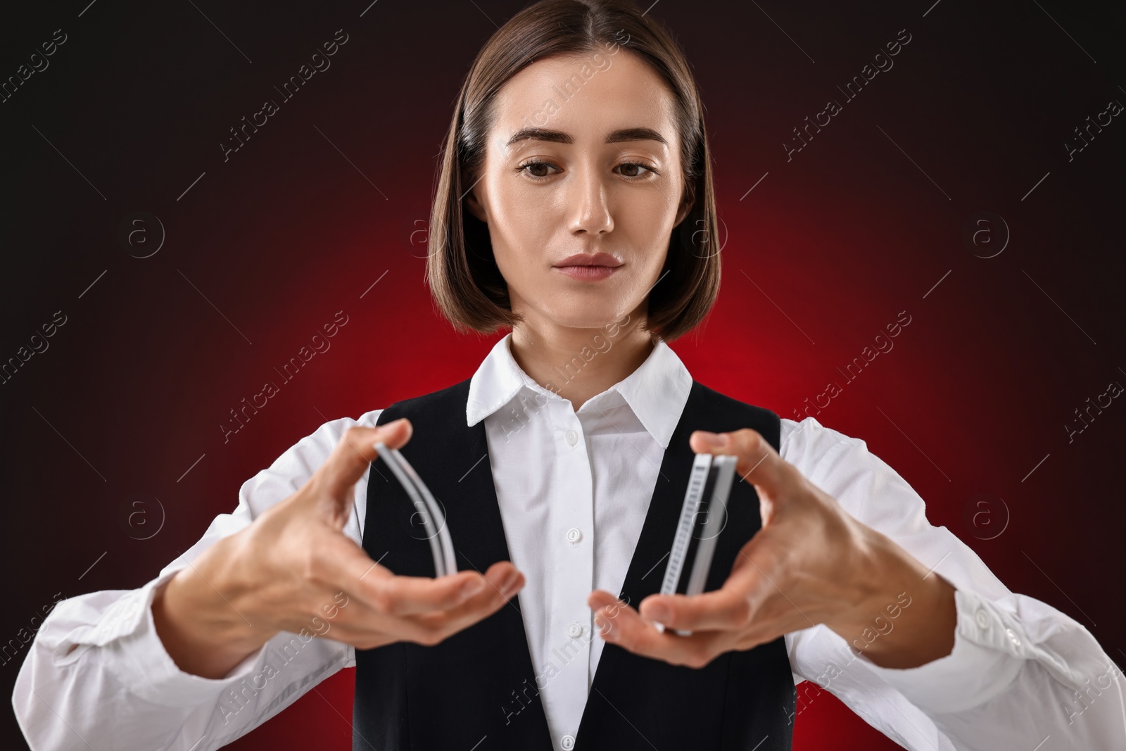 Photo of Professional croupier shuffling cards on dark red background