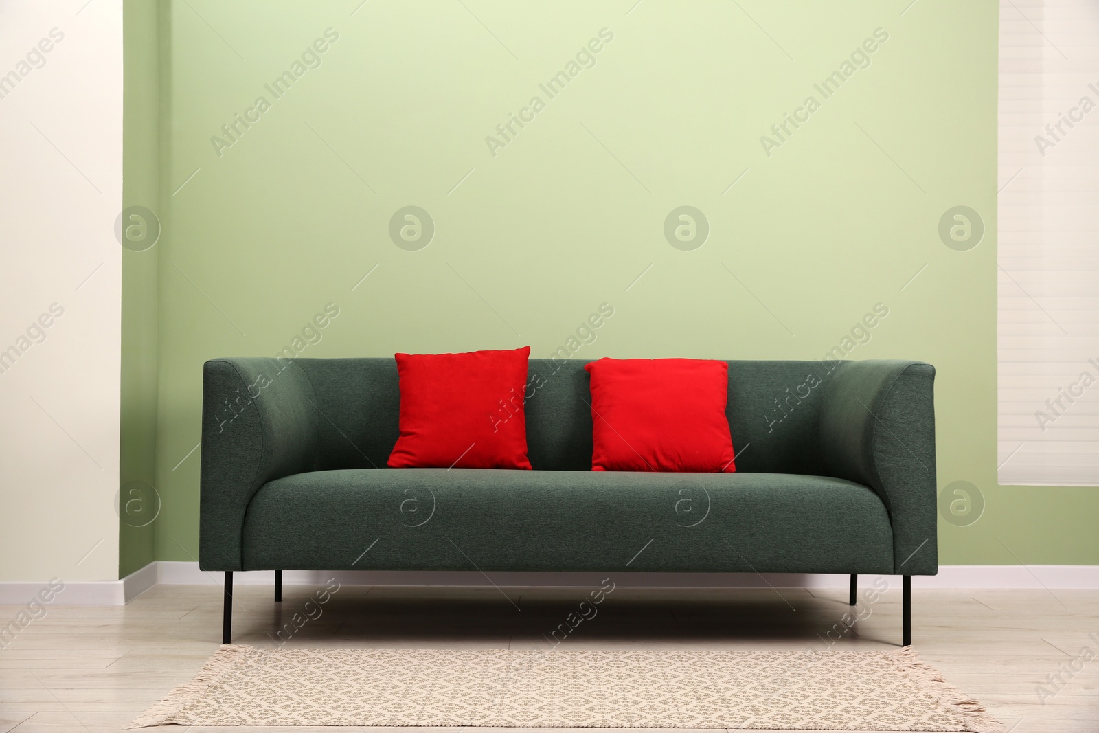 Photo of Stylish sofa with pillows near green wall indoors