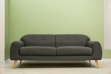 One stylish sofa near green wall indoors