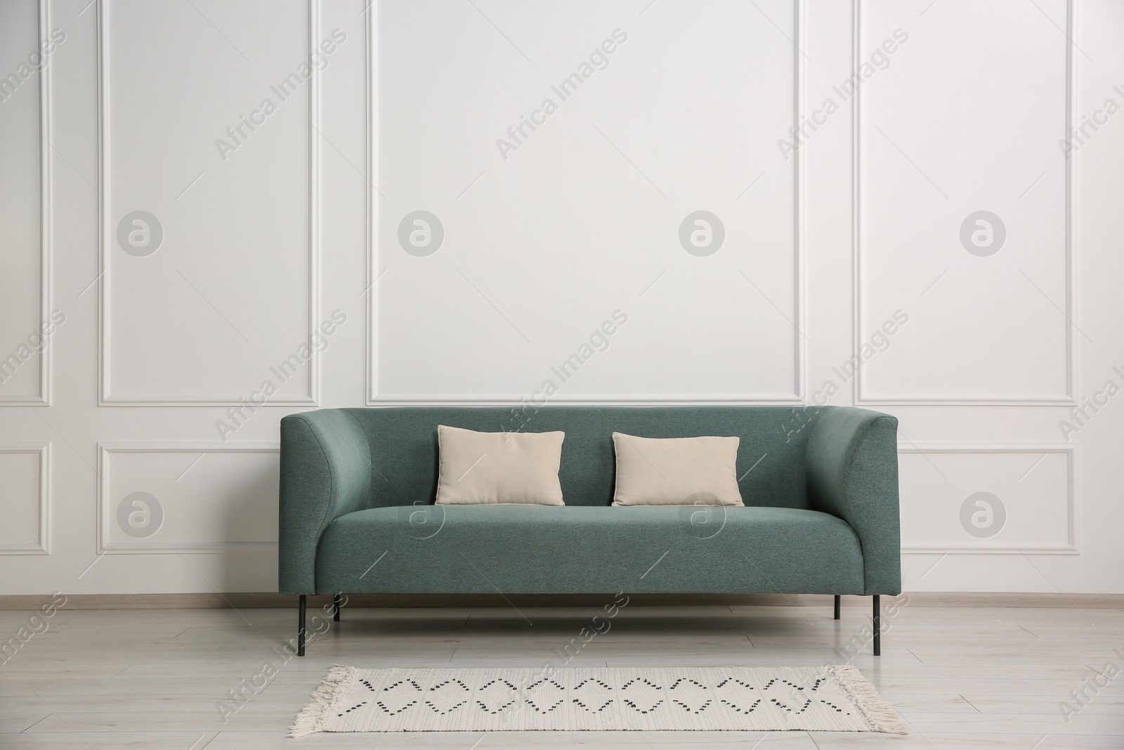 Photo of Stylish sofa with cushions near white wall