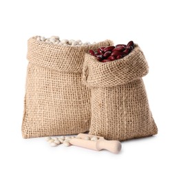 Photo of Burlap sacks with different dried beans and scoop isolated on white