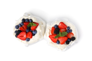 Photo of Pavlova cake (meringue dessert) with whipped cream, fresh berries and mint isolated on white, top view